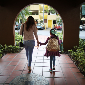 Image, mom and daughter walk hand in hand thru archway