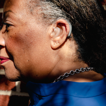 Profile of woman's face with hearing aid over and behind her ear