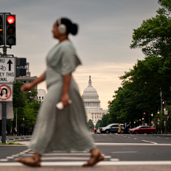 Pedestrian with headphones crosseds pedestrian in front of Capitol building