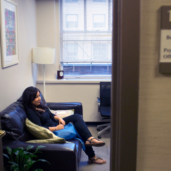 Photo, woman sits on couch in office
