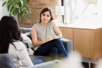 Woman talks with clipboard on couch