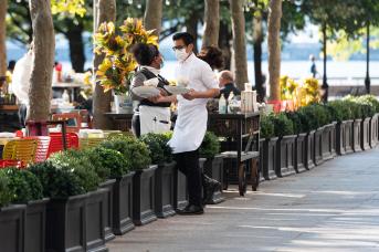  A waiter wears a face mask while carrying food outside P.J. Clarke's at Brookfield Place on September 30, 2020 in New York City.