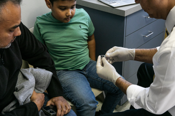 Photo, doctor shows young boy a vaccine