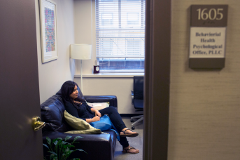 Photo, woman sits on couch in office