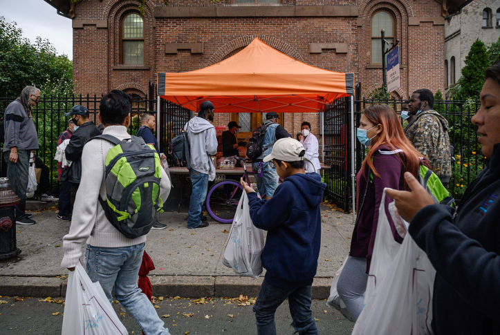 Photo, People standing in line with bags of food at soup kitchen