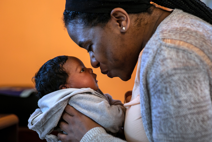 Mother leans to kiss infant son's nose