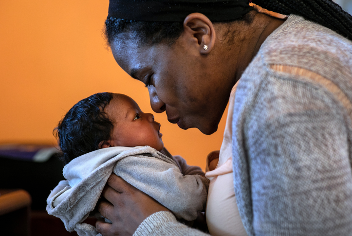 Black mother leans to kiss infant son's nose