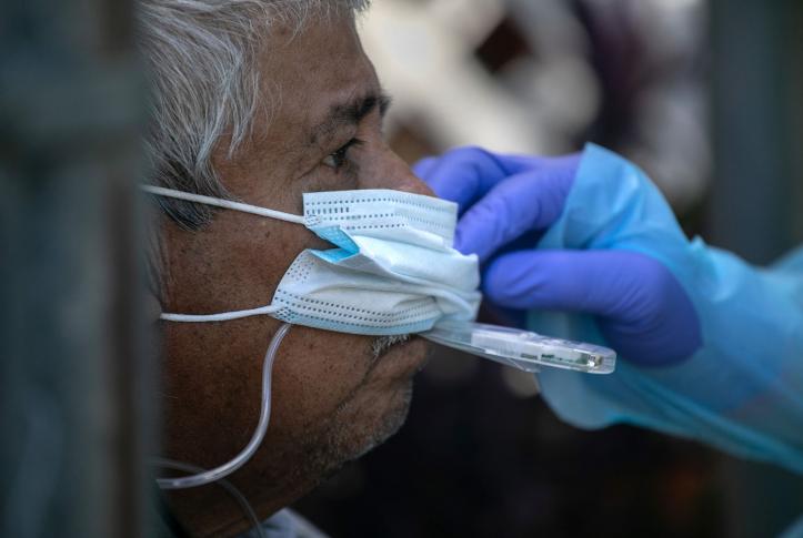 Latinx/Hispanic man getting his temperature taken by a health worker