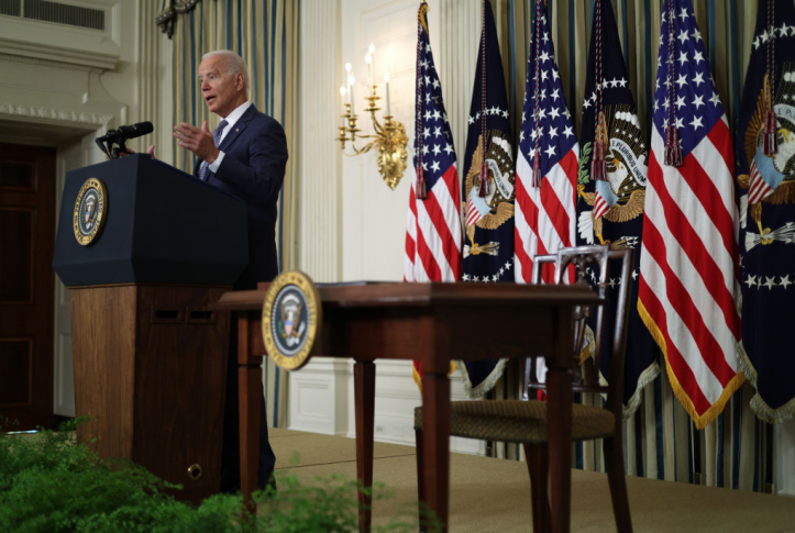 President Biden speaking at podium in front of American flags and white house seal.