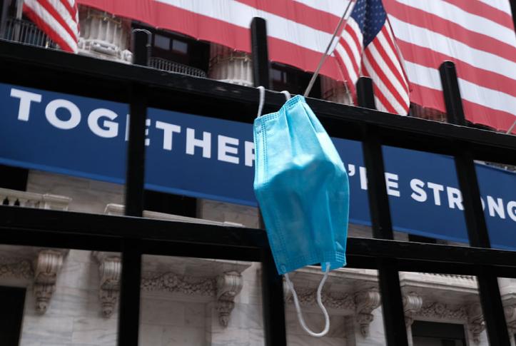 Health Care in 2020 Year in Review face mask hanging in front of the New York Stock Exchange