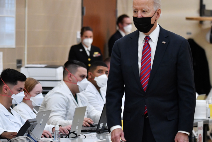 Photo, President Biden walking past health technicians wearing masks