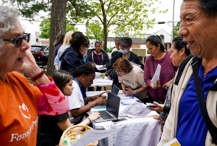 Photo, people talk on either side of a table with laptops