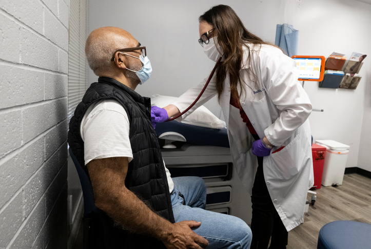 Doctor in mask examines seated patient in mask