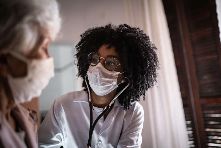 Doctor wearing a surgical mask speaks to a patient