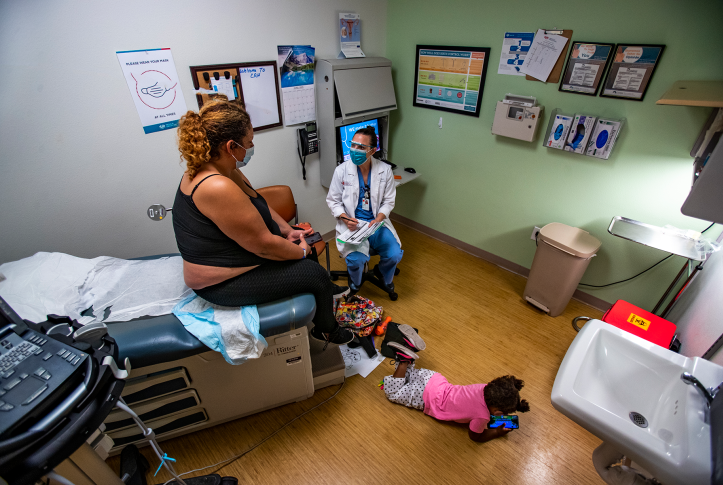 Doctor counsels patient on abortion in room with young child on floor playing