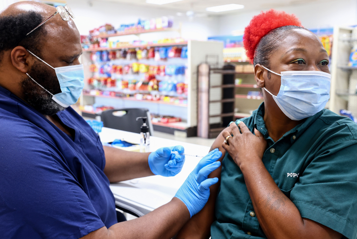 Woman in drug store in mask getting vaccine in arm
