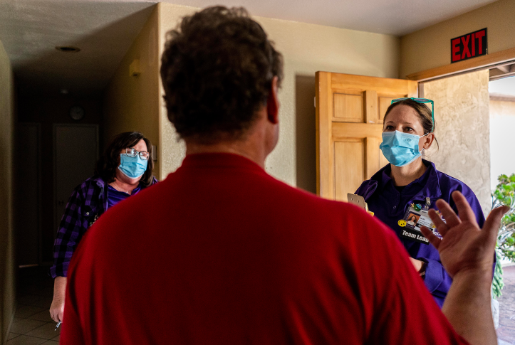 Photo, back of man talking to two masked women