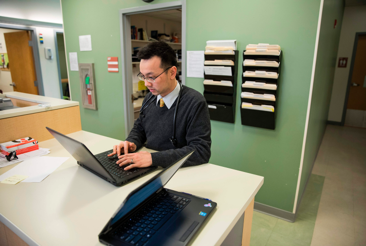 Doctor looks at patient records on laptop