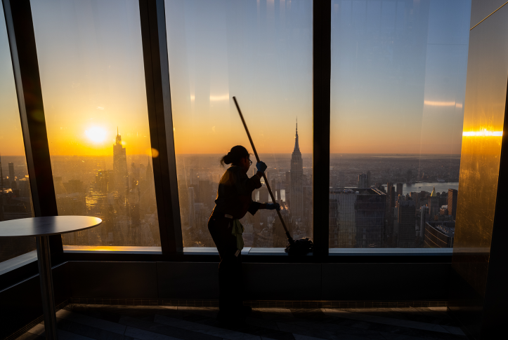 Photo, silhouette of woman pushing mop in front of NYC skyline