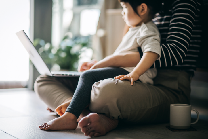 Young mother using laptop with toddler on her lap