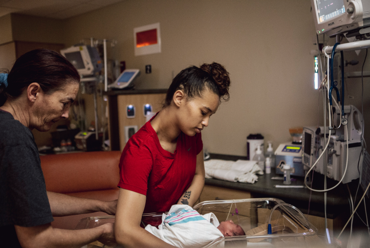 mother and newborn baby in hospital room surrounded by machines