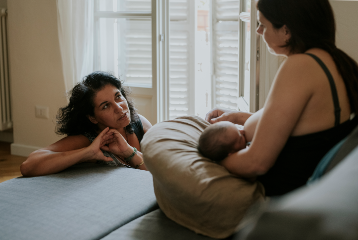 Midwife providing home breastfeeding assistance to a mother with her newborn