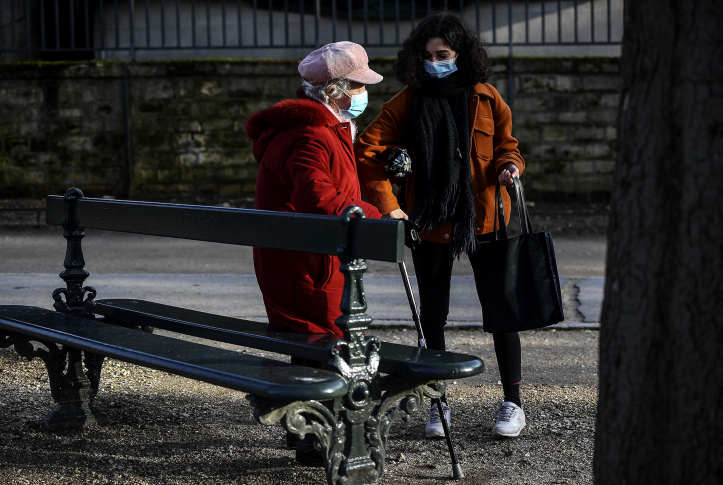 Elderly woman in mask is helped by young woman in park