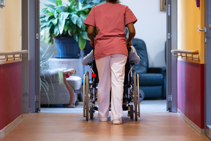 Back of nurse pushing patient in wheelchair