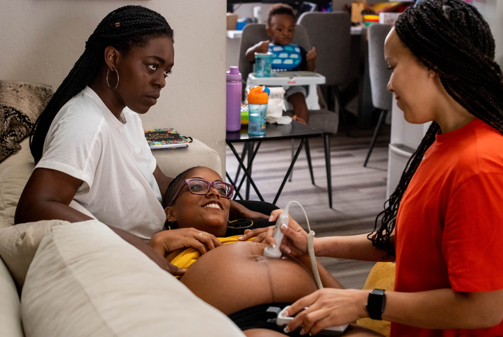 Photo, pregnant woman receiving an ultrasound by midwife