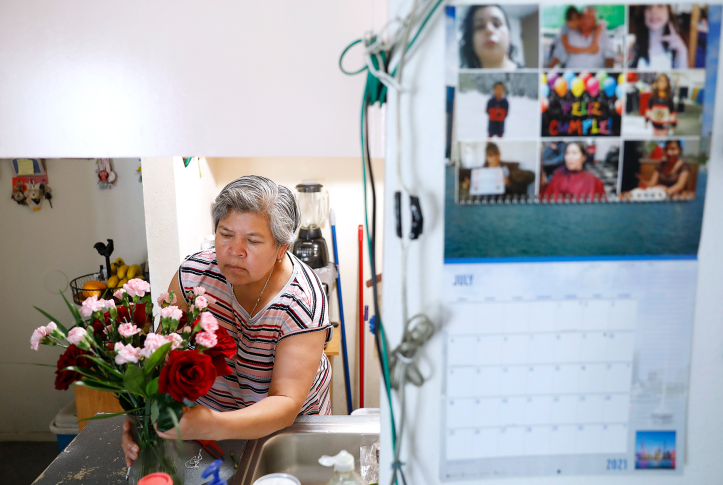 Photo, woman placing bouquet of flowers on an altar at home