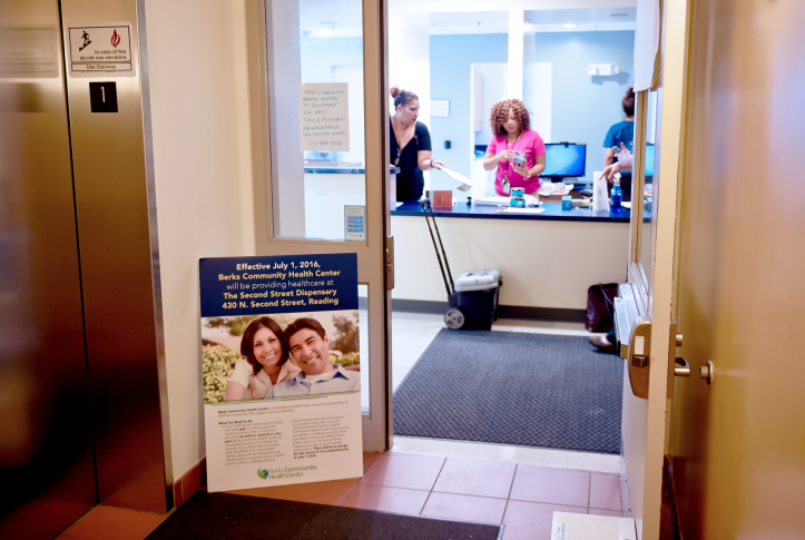 Three health care workers at the front desk behind the open door Berks Community Health Center