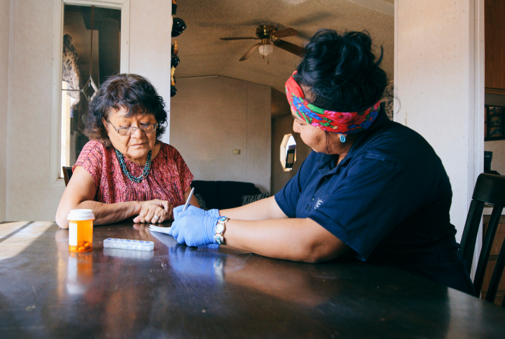 An Indigenous Navajo senior aged woman, receiving healthcare assistance in her home.