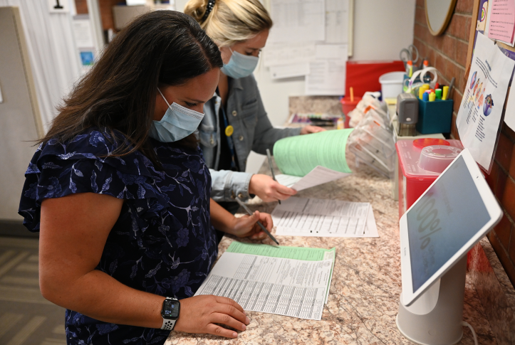 Nurses in mask stare at records