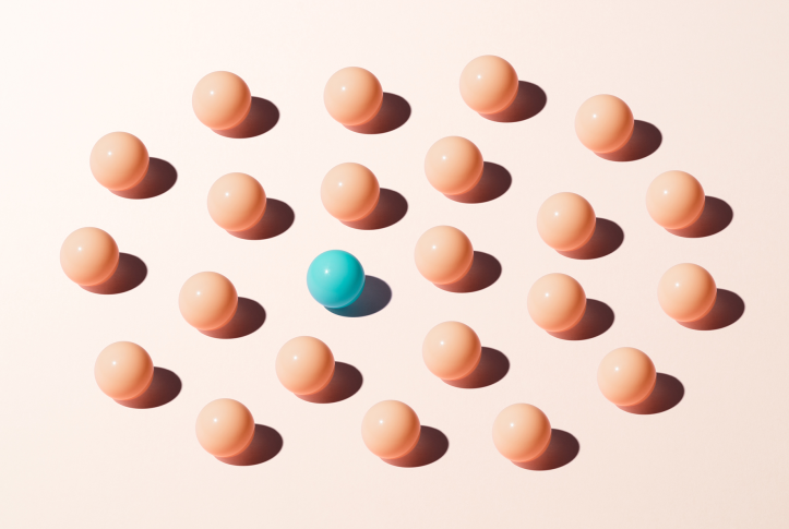wooden balls on a plain background with one blue one in the center