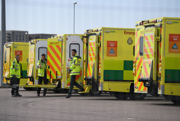 row of yellow ambulances with workers