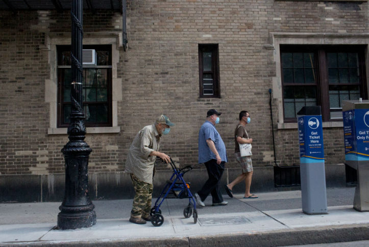 Elderly man in mask walks down city sidewalk