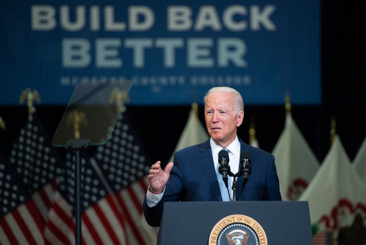 Joe Biden speaks at podium in front of "build back better" signage