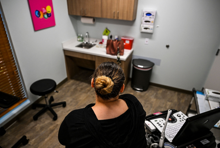woman sits on clinic table looking at an empty room