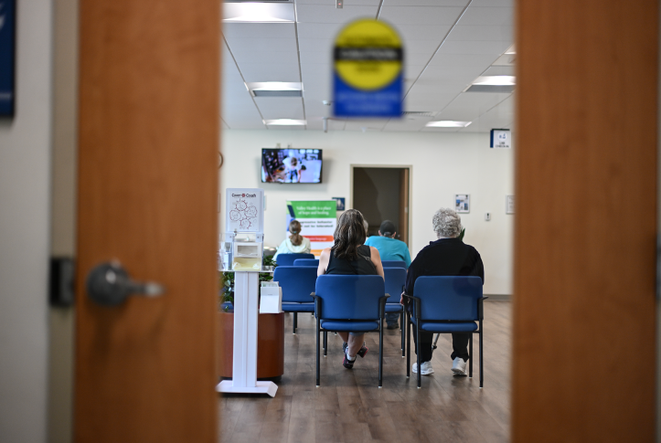backs of people seen through waiting room door