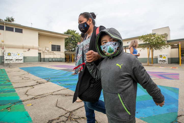 First-grade student Daniel Cano and his mom, Sonia Cano, walk past an elementary school on July 26, 2021, in Los Angeles.
