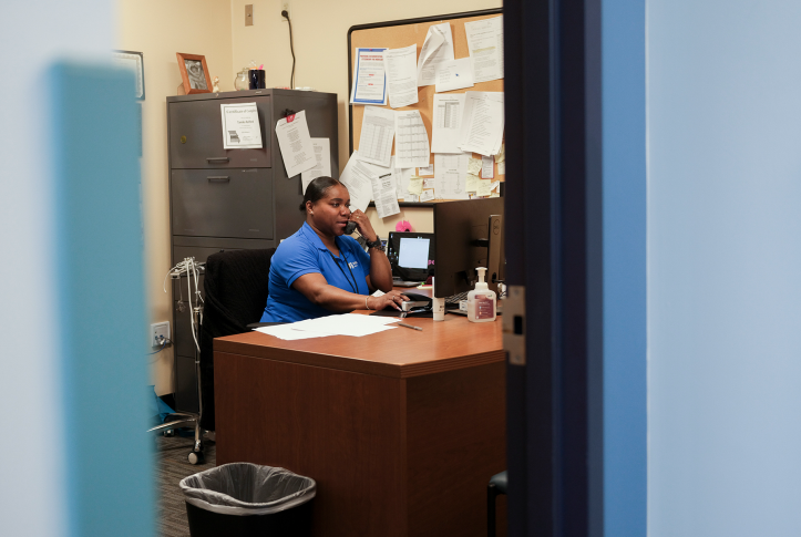 photo, woman sits behind desk on phone