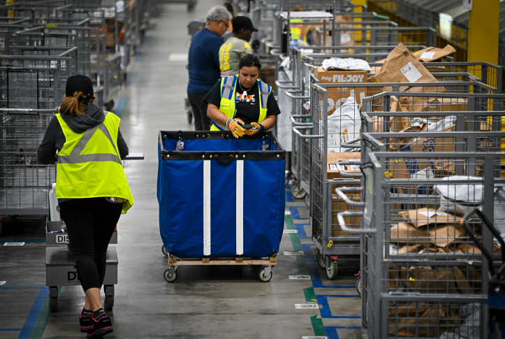 Workers in yellow vests work with packages in warehouse
