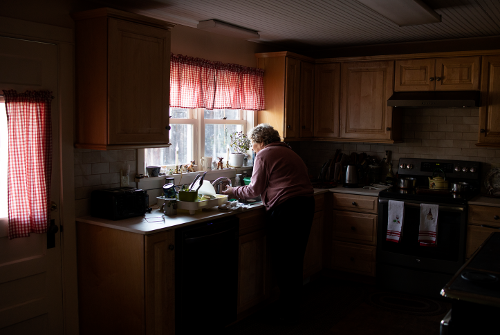 An elderly woman washes dishes in her home