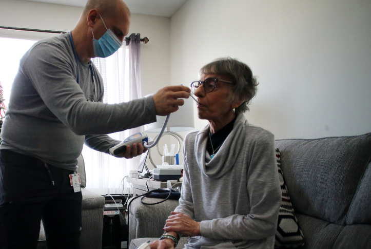 Nurse checks temperature of elderly patient in her home