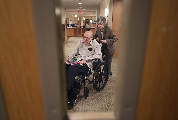 Photo, elderly woman pushing man in wheelchair