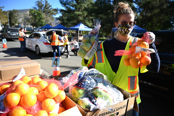 Volunteer in yellow vest loads groceries into a car