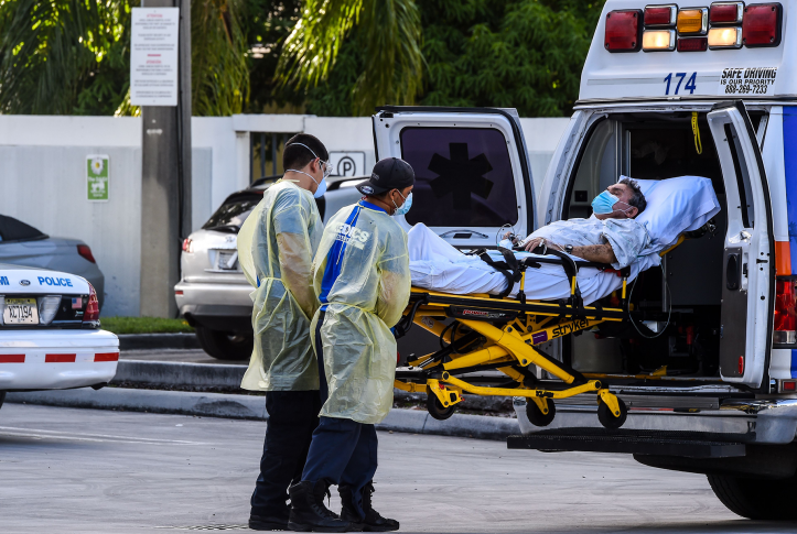Medics transfer a patient on a stretcher from an ambulance outside of Emergency at Coral Gables Hospital where Coronavirus patients are treated near Miami, Florida.