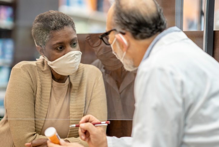 Woman and pharmacist speaking, both wearing masks