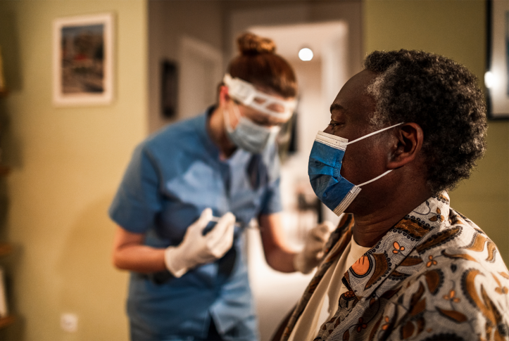 Elderly woman in mask waiting for nurse with vaccine in home