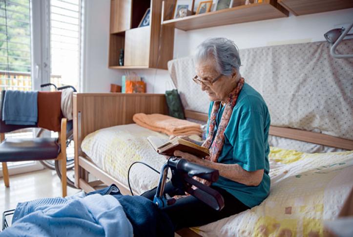 Medicare senior who is seriously ill reading on bed